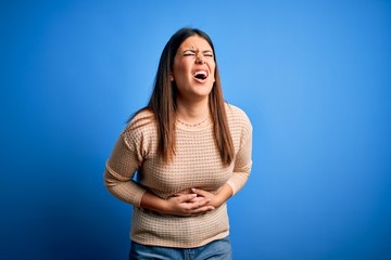 Sticker - Young beautiful woman wearing casual sweater over blue background with hand on stomach because nausea, painful disease feeling unwell. Ache concept.