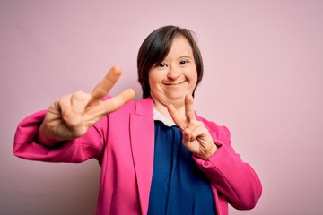 Sticker - Young down syndrome business woman over pink background smiling looking to the camera showing fingers doing victory sign. Number two.