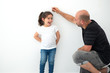© Inna - Father measuring height of a cute child. Dad measures the growth of her child daughter at a blank white wall.