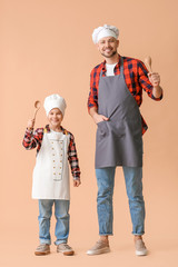 Canvas Print - Male chef and his little son on color background