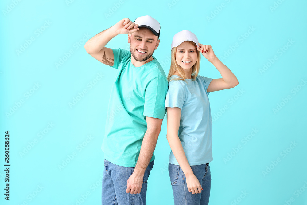 Young couple in stylish caps on color background
