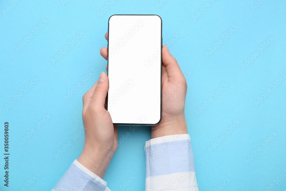 Female hands with mobile phone on color background