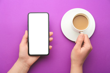 Female hands with mobile phone and cup of coffee on color background