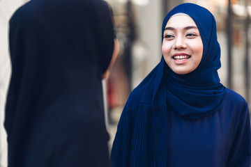 Wall Mural - Portrait of happy arabic two friend muslim woman with hijab dress smiling and talking together at store