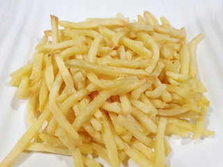 Homemade, baked french fries with herbs, salt and hot pepper made from an air fryer put on a white plate. The potato chips are a delicious and popular dish. Close up hot fast food.
