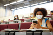 © Syda Productions - education, healthcare and pandemic concept - african student girl wearing face protective medical mask for protection from virus disease with smartphone at lecture