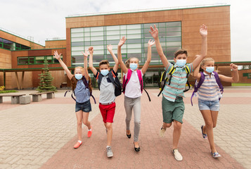 Sticker - education, healthcare and pandemic concept - group of elementary students wearing face protective medical masks for protection from virus disease with backpacks walking from school and waving hands