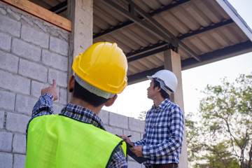 The inspectors are examining the structure of the house and note it in the clipboard to inform engineers to fix before selling to customers.