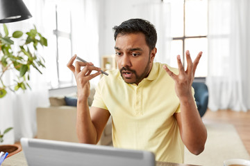 Wall Mural - technology, remote job and lifestyle concept - stressed indian man with laptop computer working and using voice command recorder on smartphone at home office