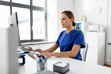 medicine, technology and healthcare concept - female doctor or nurse with computer working at hospit