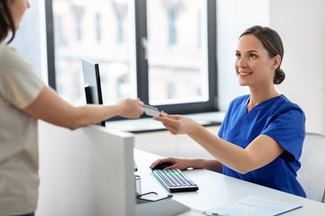 Poster - medicine, people and healthcare concept - happy smiling female doctor or nurse and patient with insurance or credit card card at hospital