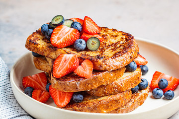 Canvas Print - Traditional french toasts with blueberries and strawberries on white plate.