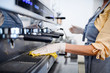 © Halfpoint - Coffee shop woman owner working with gloves , disinfecting machine.