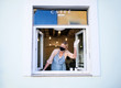 © Halfpoint - Woman with face mask serving coffee through window, shop open after lockdown.