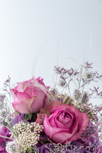 Vertical Closeup Of Bouquet Of Two Pink Roses And Different Purple And White Flowers On White Background With Copy Space