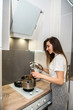 © RomanR - young woman cooking  food in a pot in the kitchen