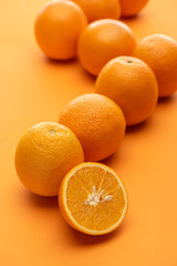 selective focus of ripe juicy whole and cut oranges on colorful background