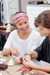 © DragonImages - Smiling woman enjoying making jewelry in studio with her friends