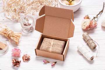 Bar of homemade soap wrapped in hemp fabric on wood background