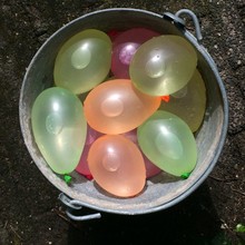 Directly Above View Of Water Filled Balloons In Bucket On Field