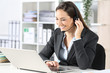Happy telemarketer with laptop attending call at office
