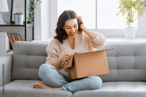 Fotomural woman is holding cardboard box sitting on sofa at home