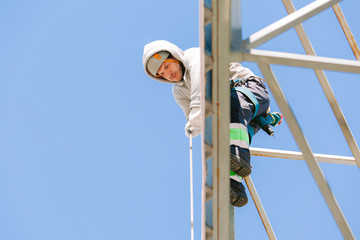 Industrial climber in helmet and overall working on height. Risky job. Professional worker