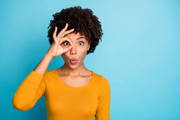 Poster - Portrait of astonished crazy afro american girl make okay sign binocular eye watch her neighbors impressed stare stupor wear bright pullover isolated over blue color background