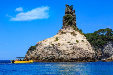 A tour boat at the base of a rock stack jutting from the ocean near Hahei on the Coromandel Peninsula, New Zealand