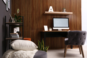 Poster - Comfortable workplace with computer near wooden wall in stylish room interior. Home office design