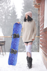 Wall Mural - Young woman with snowboard wearing winter sport clothes outdoors