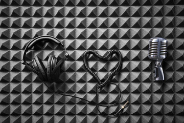 Wall Mural - Retro microphone and professional headphones lying on acoustic foam panel background