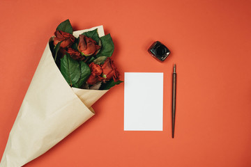 Set of vintage dip pen, inkpot and blank paper sheet on red background