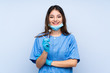 Woman dentist holding tools over isolated blue background laughing