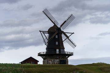 Old Windmill on a hill in south Sweden with cloudy sky in the background.