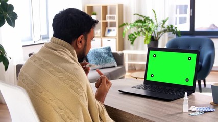 Poster - healthcare, technology and people concept - sick indian man in blanket with thermometer having video call on laptop computer with chroma key green screen at home