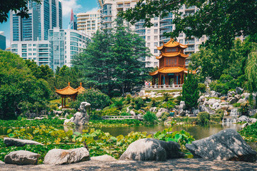 Beautiful Chinese garden and pond surrounding a pagoda contrasted by Sydney city in the background. Chinese Garden of Friendship, Sydney, Australia.