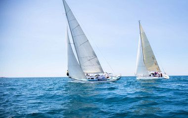 two white motor yachts with raised sails take part in the regatta. a strong wind tipped the ship. wa