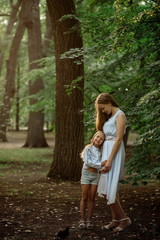 Beautiful girl 7 years old with long blonde hair with a blonde mom walk and cuddle at sunset in the summer park