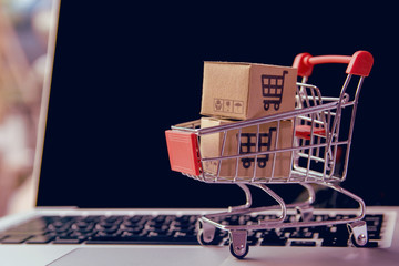 Shopping online concept - Parcel or Paper cartons with a shopping cart logo in a trolley on a laptop keyboard. Shopping service on The online web. offers home delivery..