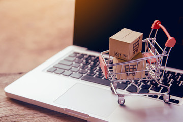 Shopping online concept - Parcel or Paper cartons with a shopping cart logo in a trolley on a laptop keyboard. Shopping service on The online web. offers home delivery..