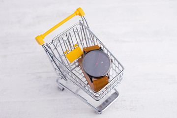 Photo of yellow trolley with hand watch , shopping online concept