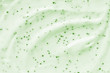 Face cream scrub texture background. Green color exfoliating skincare product smear smudge swatch. Gentle creamy scrub cleanser strokes closeup