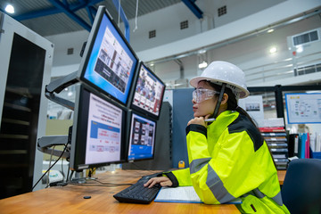Inside the large Industry Factory Female Computer Engineer Works on Personal Computer She coding program for control machine,Thailand people work on fours monitors,Programmer working with serious