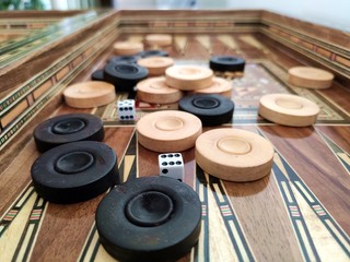 Backgammon with wooden inlay. Wooden backgammon board game of pearl inlaid on brown background.