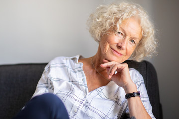 Wall Mural - smiling older woman relaxing on sofa at home