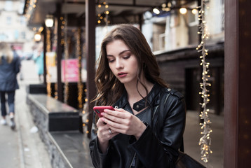 pretty european woman is using smartphone sitting on city background