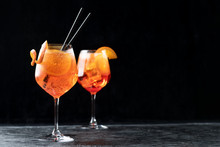 Two Glasses Of Classic Italian Aperitif Aperol Spritz Cocktail With Slice Of Orange On Dark Background, Traditional Summer Fresh Drink, Copy Space