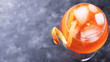 Classic italian aperitif aperol spritz cocktail in glass with ice cubes and with slice of orange on dark background, traditional summer fresh drink, close up and top view, web banner