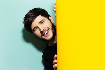 Wall Mural - Studio portrait of young happy guy between two backgrounds of yellow and aqua menthe colors.